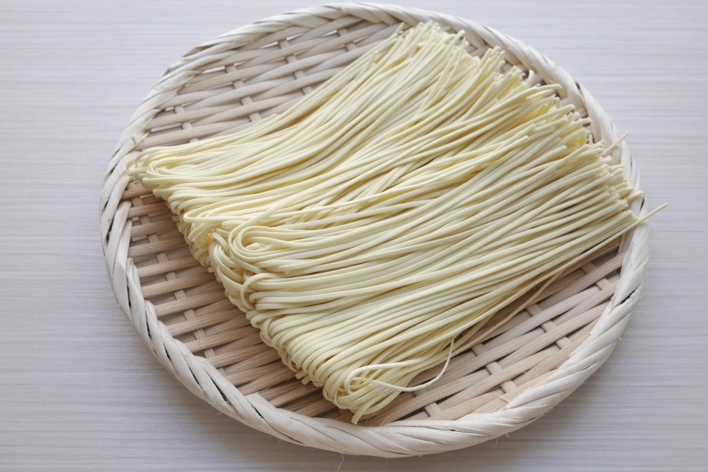 A bundle of fresh, uncooked ramen noodles, neatly coiled.
